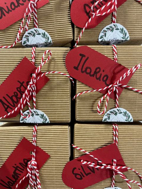 Pacchetti regalo di Natale in carta kraft con etichette rosse personalizzate con i nomi