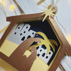 Presepe natalizio in carta esposto su una mensola, idea regalo